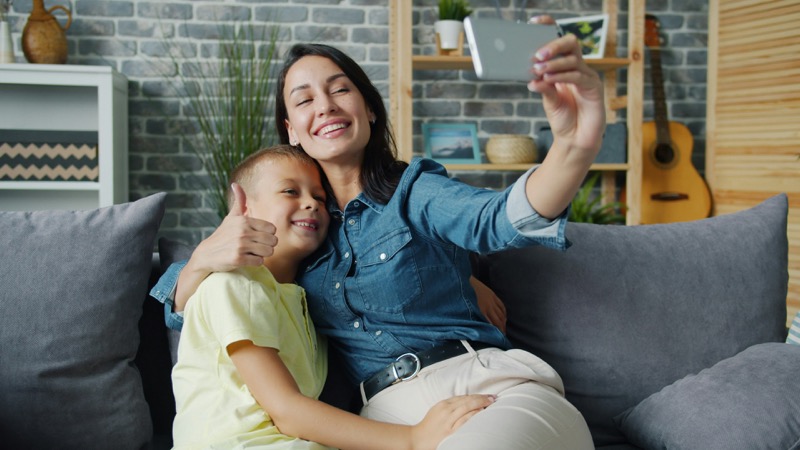 Parent taking a selfie with their child on a couch